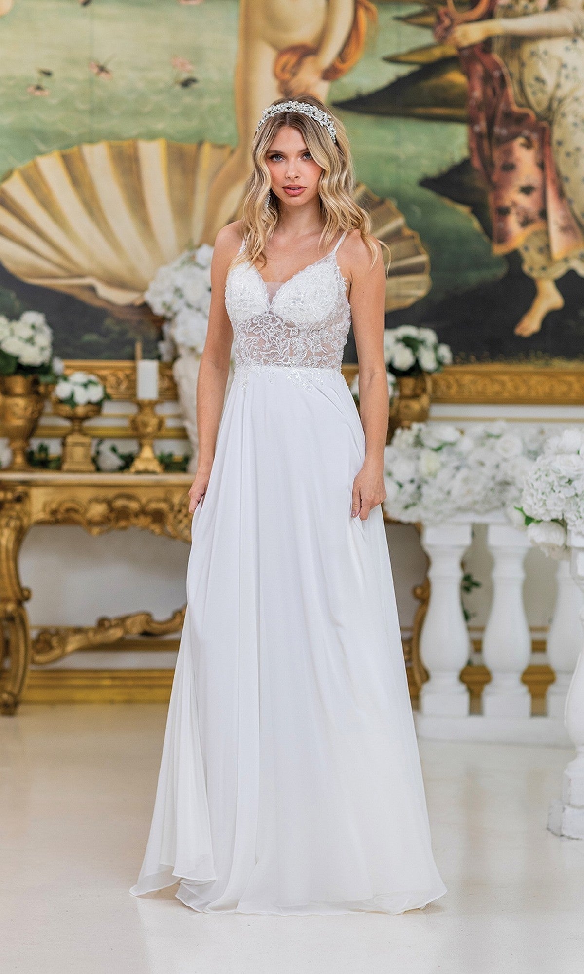 A woman wears the Dancing Queen 4500 Long Prom Dress in off white, featuring lace, chiffon, and beaded embroidery, as she stands indoors before an ornate gold table with floral decorations.